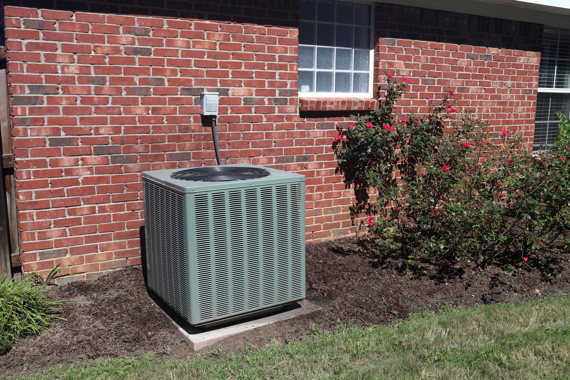 HVAC Condenser unit next to brick home.